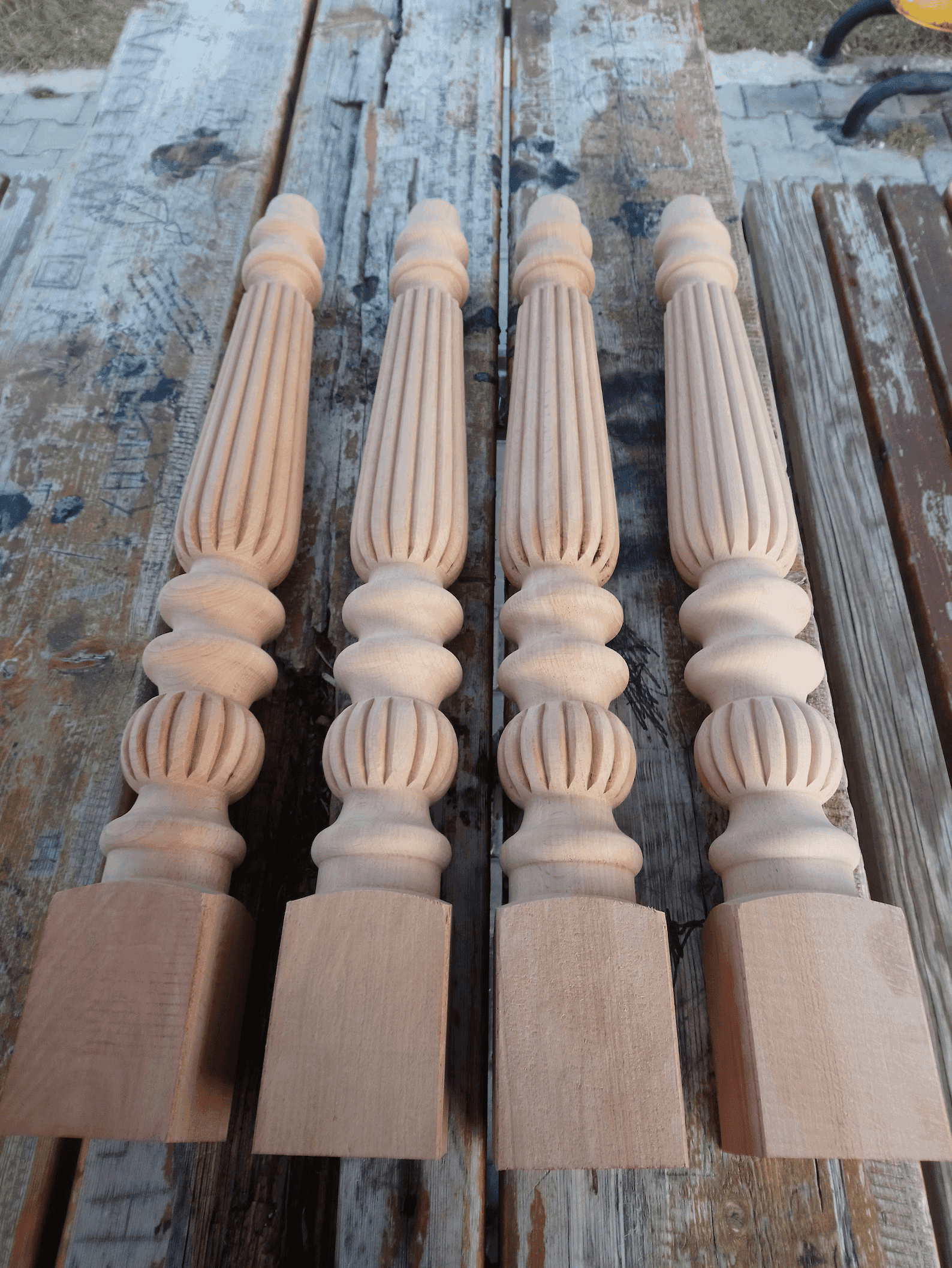 Four hand-turned fluted wooden table legs with reeded detailing, freshly turned in pale timber
