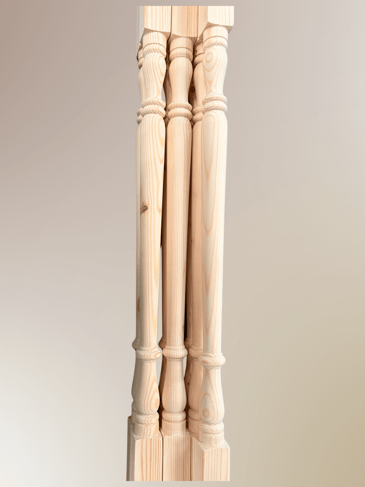 Vertical close-up of pine wood spindle shafts with decorative ring-turned collar at the top and a turned foot at the base