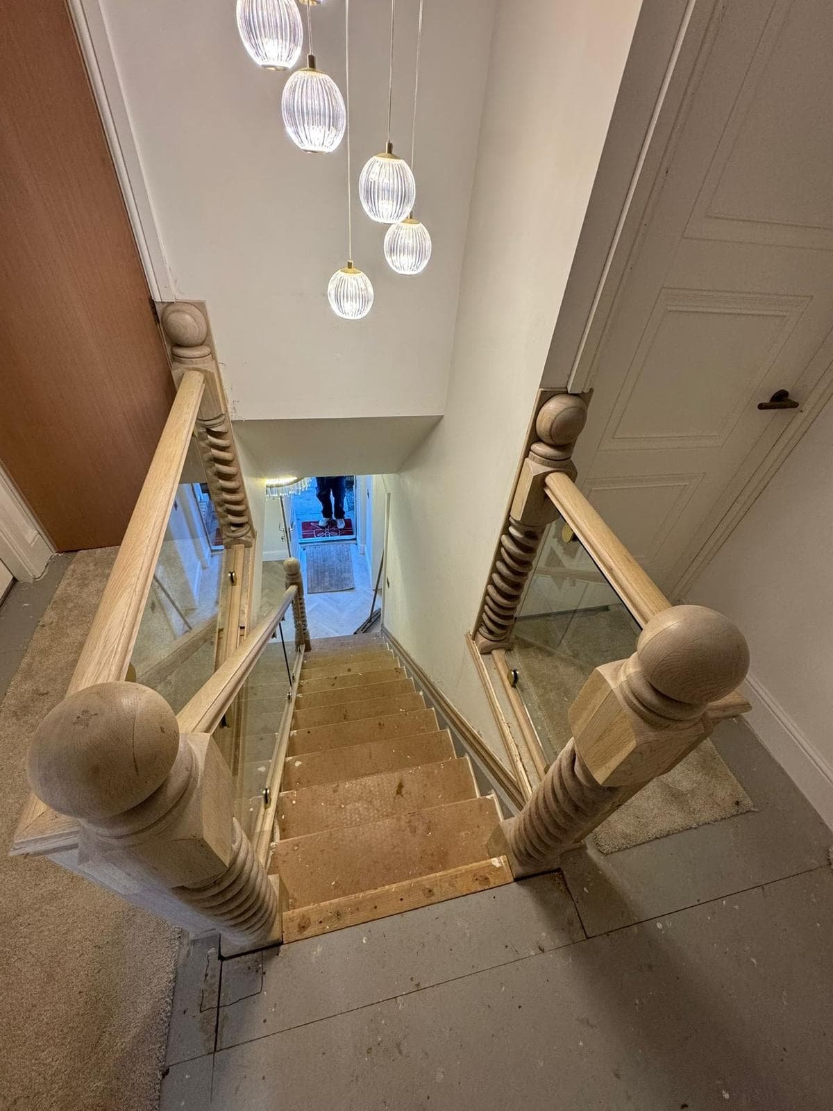 View down an oak staircase flight with barley-twist newel posts and a glass balustrade